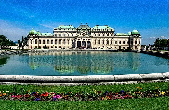 The Upper Belvedere reflected in its pond, with flower beds in the foreground