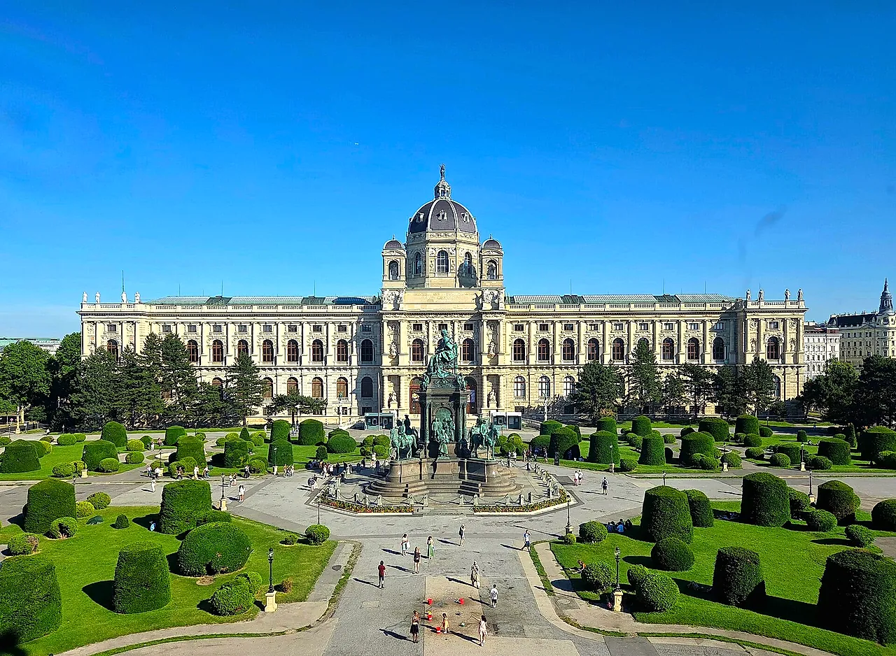 The Kunsthistorisches Museum seen across Maria-Theresien-Platz, with its clipped hedges and the Maria Theresa monument, on a clear blue day